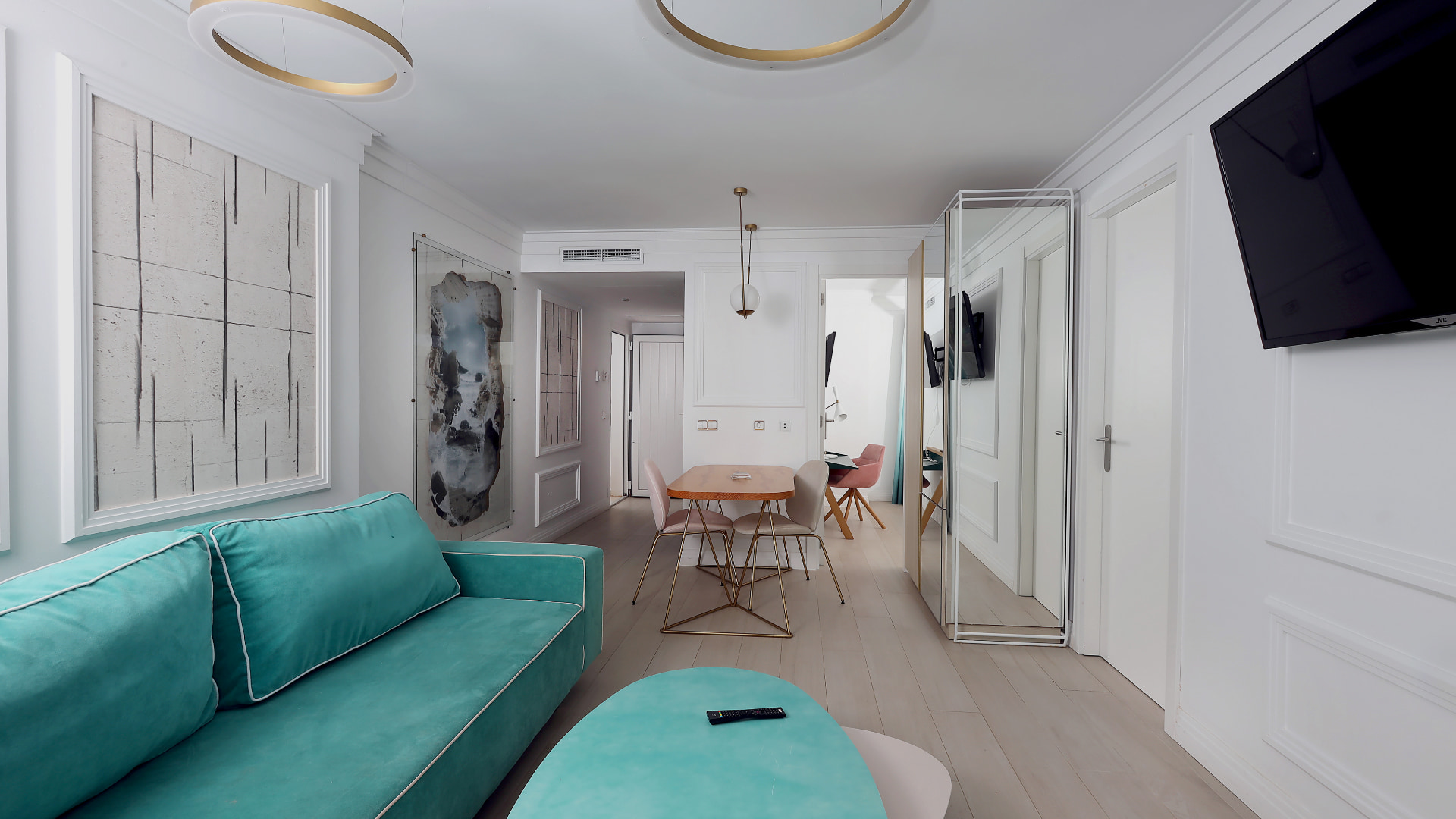 Zona de estar de la suite con sofá, televisión de pantalla plana, mesa de salón comedor, espejos de cuerpo completo e iluminación led