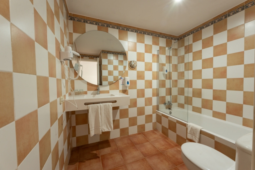 Bathroom with bathtub, toilet, sink and amenities of the one-bedroom apartment
