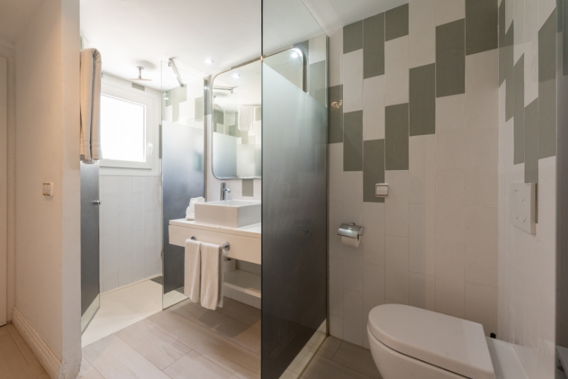 Badezimmer mit Dusche, Toilette, Waschbecken und Spiegel.